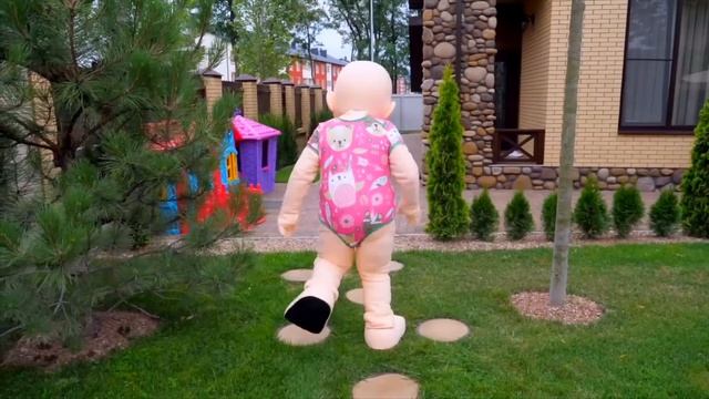 Настя играет с забавной большой куклой-младенцем