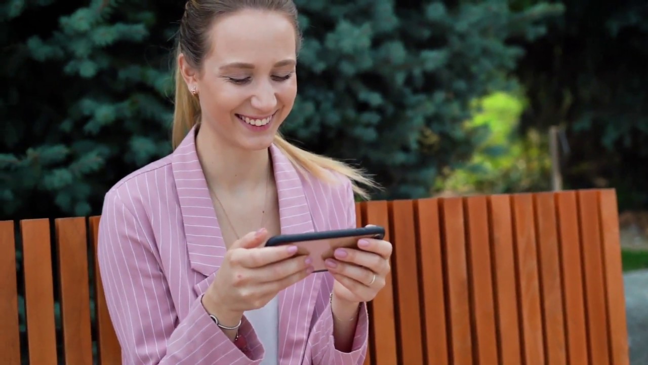 Счастливая девушка смотрит на смартфон