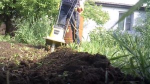 Работа электрокультиватором во дворе - культиватор рвёт сорняки и закапывает их в землю