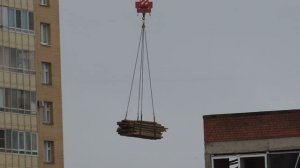 Загрузка Камаза башенным краном, под дождём - Стоит КамАз с угла дома, его грузит строительный кран.