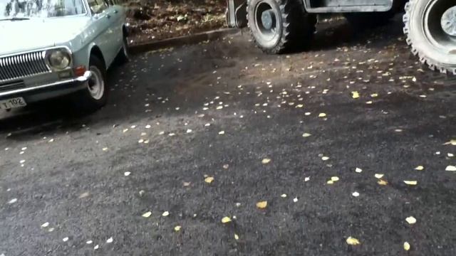 Экскаватор гладит землю во дворе.