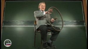 Человек на скамье Жуковского с велосипедным колесом