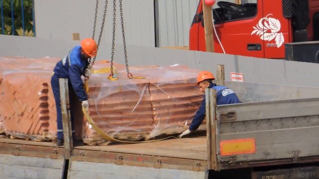 Автокран выгружает из грузовика кирпич, подаёт на стройку на цокольный этаж. смотреть онлайн