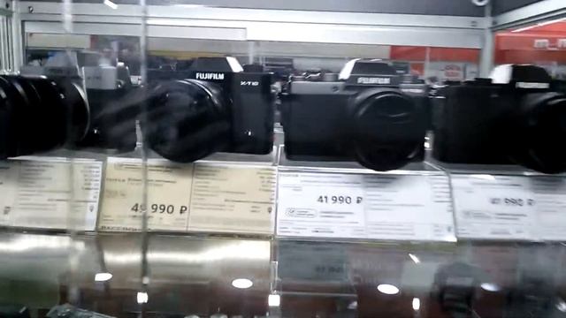 Системные фотоаппараты Canon и Fujifilm в магазине. За стеклянной витриной. смотреть онлайн