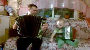 маленький мальчик играет на гармошке.