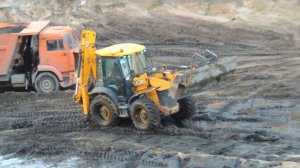 Экскаватор погрузчик ровняет площадку с грязью