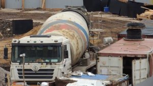 Автобетономешалка едет задним ходом аккуратно вдоль котлована.