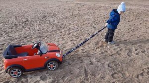 машинка буксует по песку. Антоша вытягивает машину