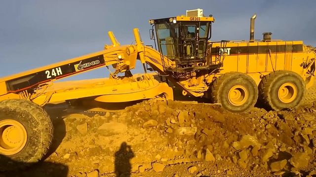 CAT 24 Grader Trimming Rock Slope