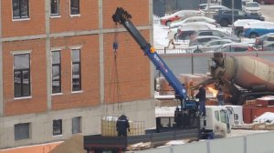 Манипулятор разгружается а на заднем плане у Бетономешалки, что то поджигают.