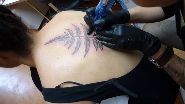 Emilia tattoos a fern on the center of the upper back @House of Tattoos Amsterdam. смотреть онлайн