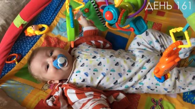 Как малыш лежит на коврике выплевывает соску и радостно общается.