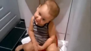 Маленький мальчик поет,сидя на горшке.