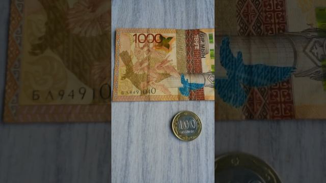 МОНЕТА СТО И БАНКНОТА 1 000 ТЕНГЕ лежат решкой и № серии на серой поверхности Двенадцатого Августа смотреть онлайн