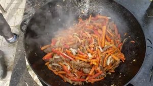 Китайская лапша вок в казане на костре.