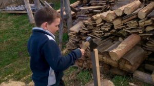 Восьмилетний мальчик колет дрова