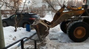 Работает трактор, убирает снег во дворе