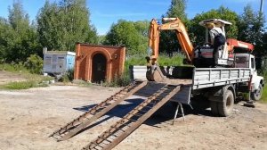 Мини экскаватор съезжает с эвакуатор, манипулятора.