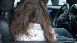 Волосы девушки развеваются от мощного звука в машине.