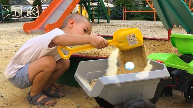 Дамир распаковывает новый педальный трактор, весело катается на площадке и грузит песок в прицеп. смотреть онлайн