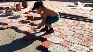 Норик укладывает плитку во дворе