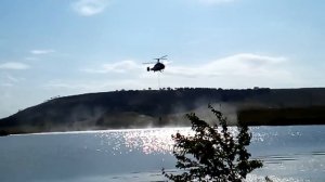 Пожарный вертолёт набирает воду из водоёма