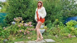 Рыжая красотка в оранжевой юбке и в беежевых колготках на каблуках танцует