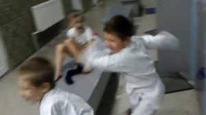 Дети в кимоно играют и дерутся в раздевалке.