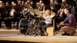 3 летний мальчик играет на барабанах с классическим оркестром