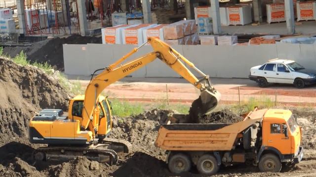 Экскаватор на гусеницах грузит землю в Старенький Самосвал