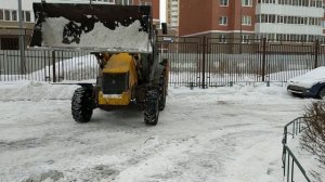 Трактор чистит снег в городе