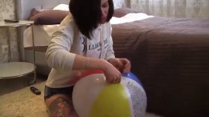 Девушка лопает пляжный мячик