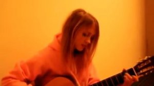 Девушка очень красиво играет на гитаре и поет новую песню