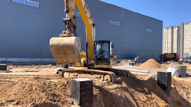 Гусеничный экскаватор CAT319 DLN копает траншею коммуникаций