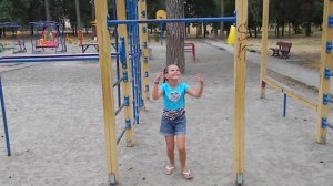 Маленькой девочке нравится висеть на турнике и брусьях, делать разные трюки, подтягиваться