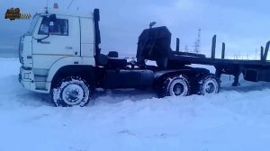 На Грузовике КамАЗ в снегу с прицепом, пытается проехать заснеженный участок дороги.
