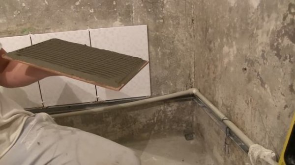 Укладка первого ряда плитки на стене