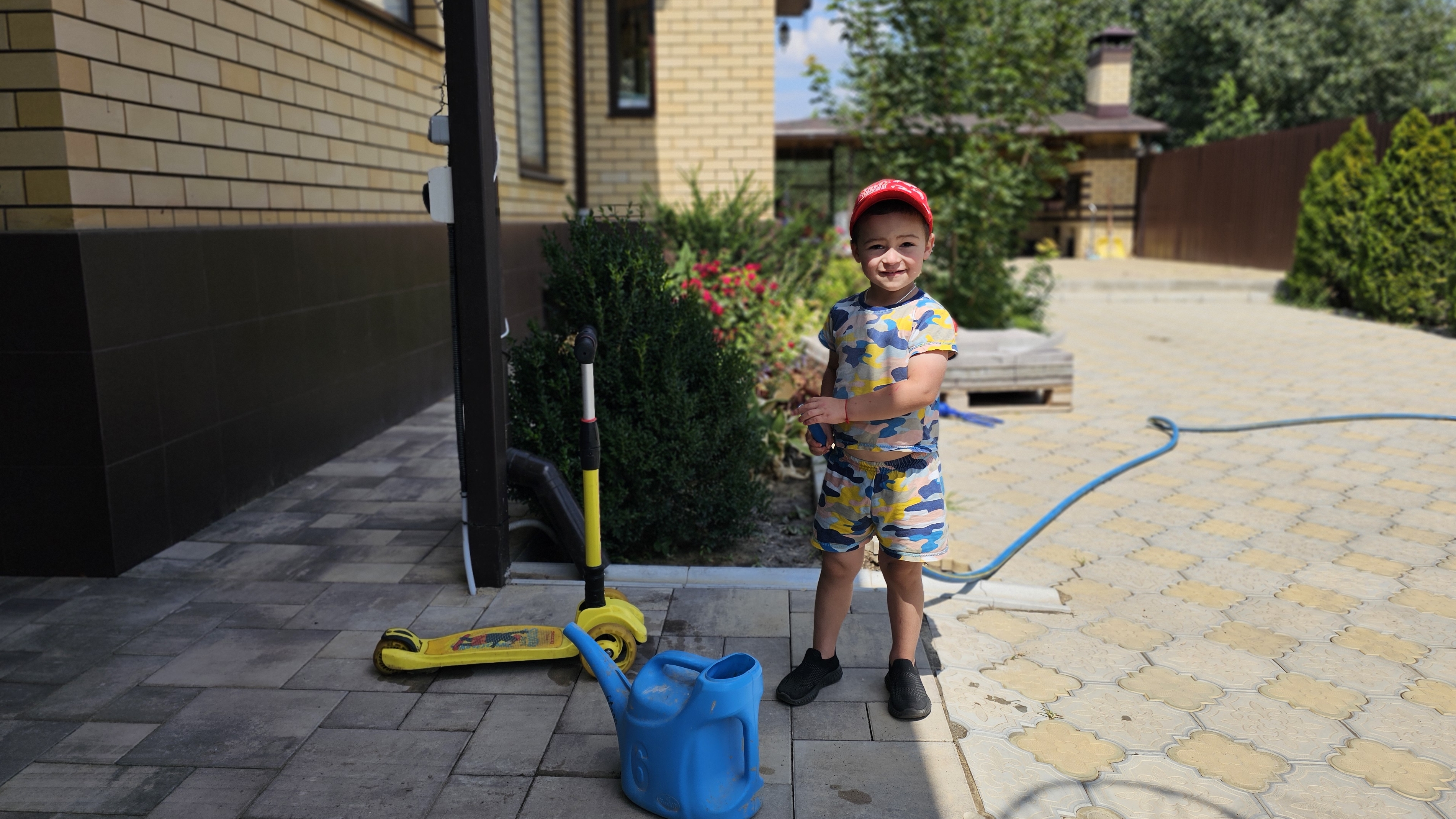 Андрюшка поливает цветы и самокат