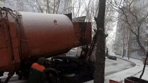 Мусоровоз зимой. Замело контейнеры с мусором. Загрузка мусора в снегопад.