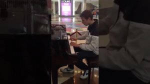 Парень красиво играет в торговом центре на пианино