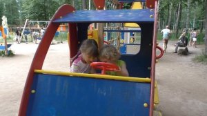 Дети катаются с горки, качаются на качелях на детской площадке в парке.