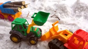 про трактор.  Трактор с прицепом разгружает бревна.  Тракторишка