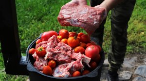 Томатный суп подлива с говядиной и сухариками в казане на костре.