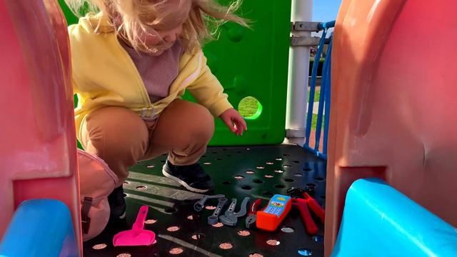 Ева играет на детской площадке с разными игрушками и машинками