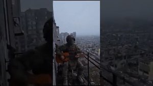 Русский солдат играет на гитаре на фоне полностью разрушенного Бахмута