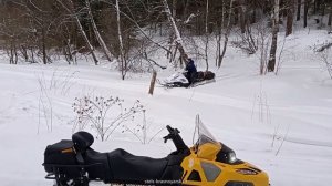 Снегоход STELS СТАВР 600 в глубоком снегу на косогоре между деревьев в подъем