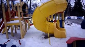 Близнецы на детской площадке с трубой для спуска и горками зимой. Подвесной мост.