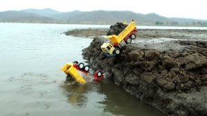 Желтый экскаватор вытаскивает из реки машинку