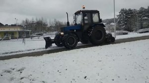 Трактор со щеткой  чистит снег. Уборка первого снега.