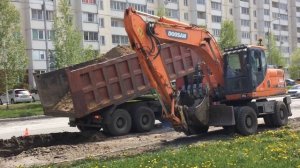 Экскаватор копает яму на дороге